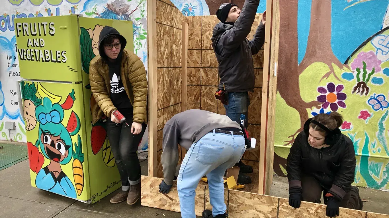 Volunteers building a fridge shelter